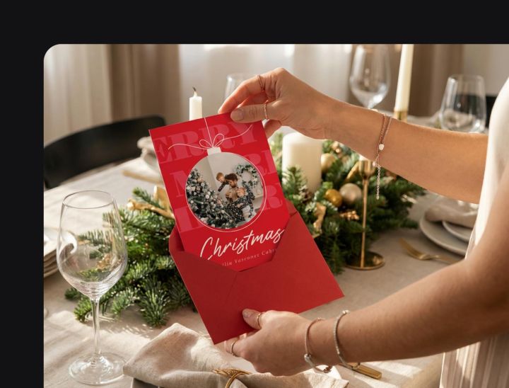 Mujer sosteniendo una tarjeta navide&ntilde;a con foto sobre una mesa decorada &mdash; tarjeta navide&ntilde;a con foto personalizada