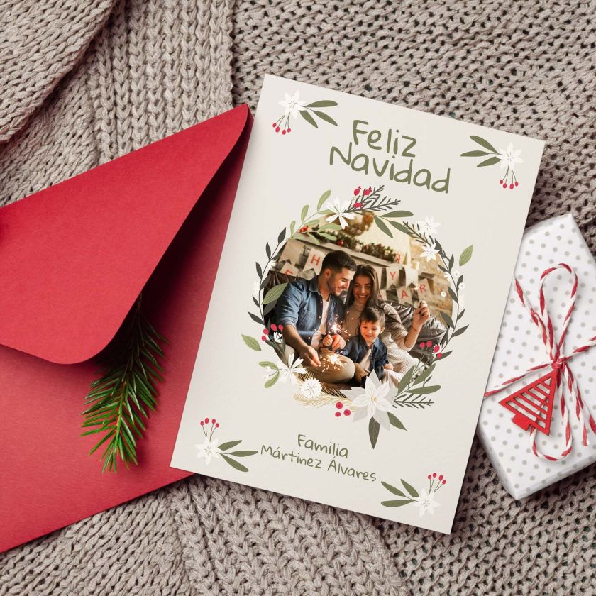 Mockup de tarjeta navide&ntilde;a con foto personalizable colocada junto a sobre rojo y decoraci&oacute;n navide&ntilde;a