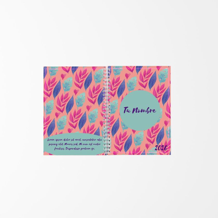 vista abierta de una agenda personalizada con fondo coral y patr&oacute;n de hojas rosadas y azules, encuadernada con espiral blanca y texto "Tu Nombre 2026"