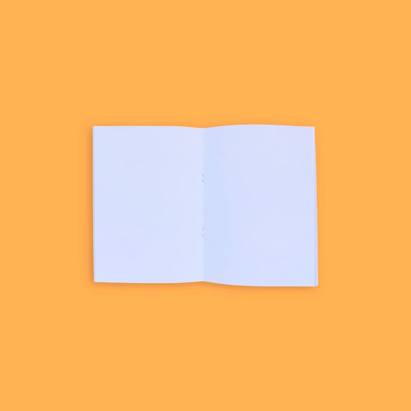 libreta grapada abierta mostrando páginas interiores en blanco sobre fondo naranja