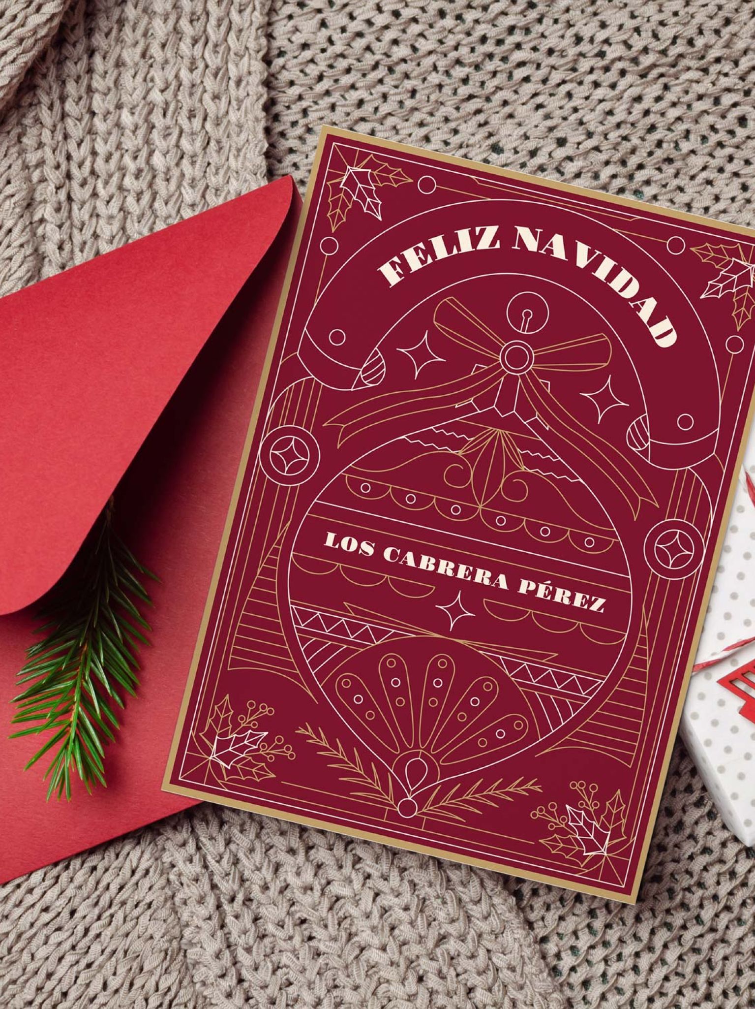 Mockup de tarjeta navideña personalizada colocada junto a sobre rojo y regalo decorativo