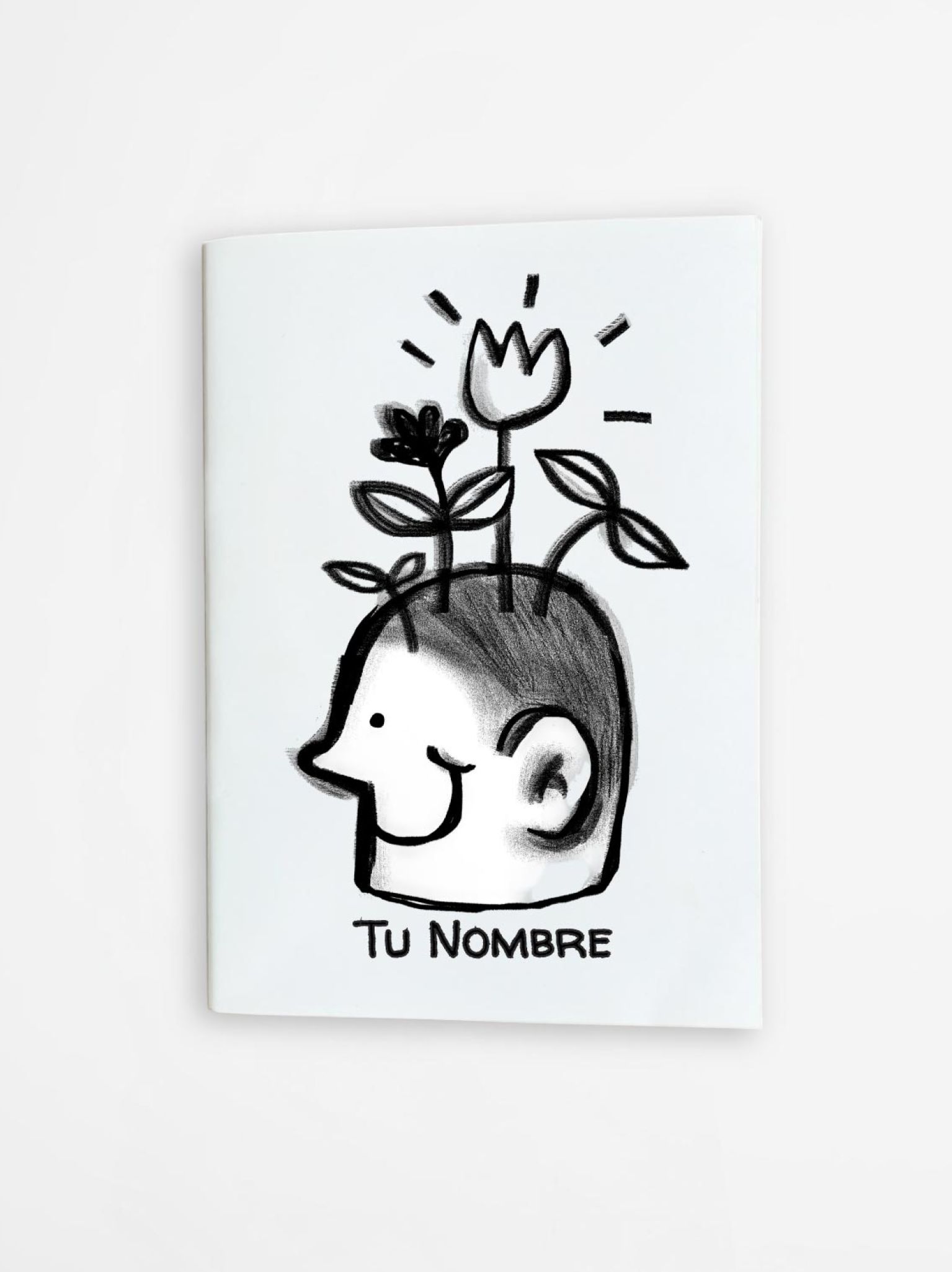 libreta art&iacute;stica con dibujo en blanco y negro de una cabeza sonriente con plantas y flores, personalizable con tu nombre