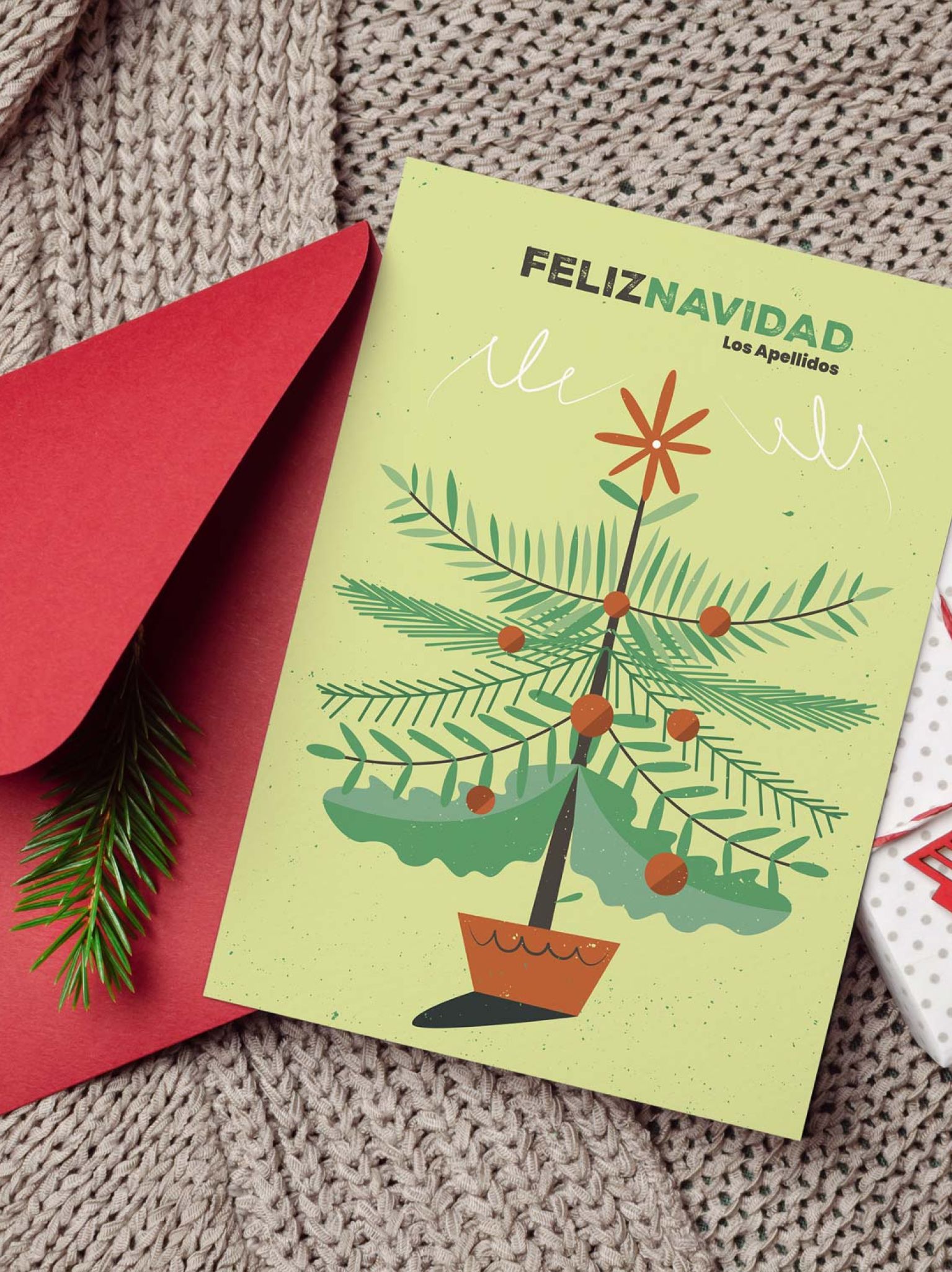 Tarjeta navideña personalizada con árbol ilustrado, sobre rojo y decoración navideña en fondo de punto