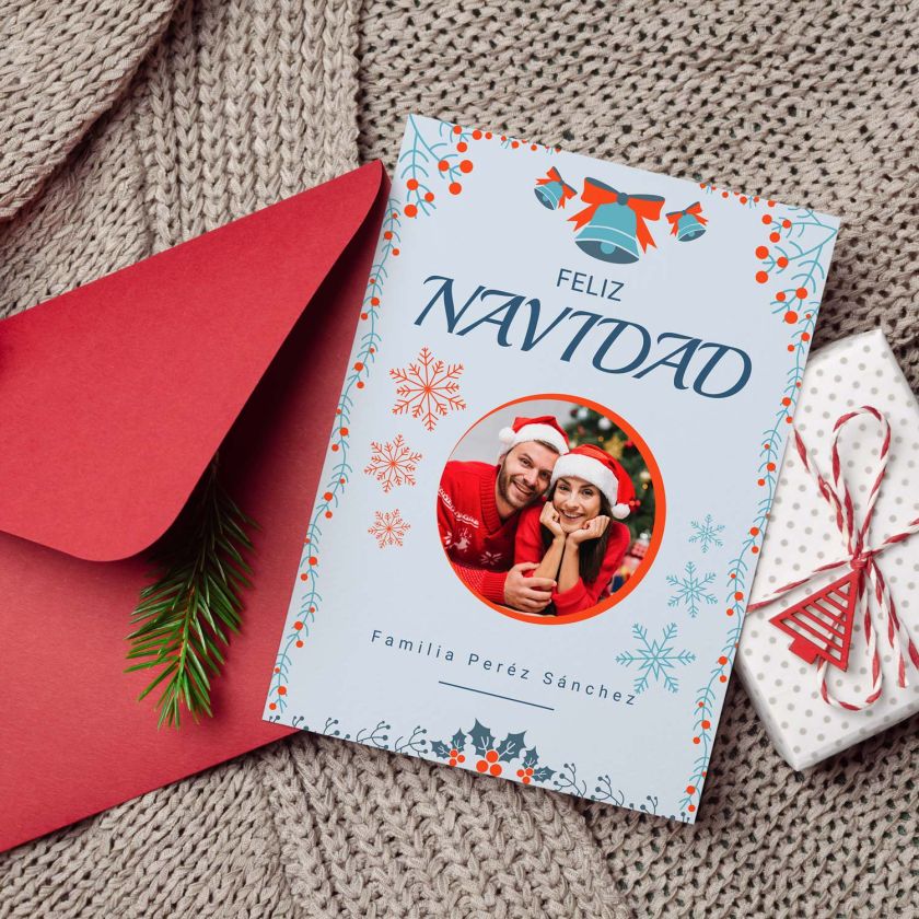 mockup de tarjeta navidad con foto personalizada junto a sobre rojo y decoración navideña