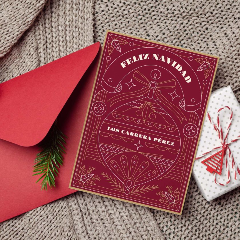 Mockup de tarjeta navideña personalizada colocada junto a sobre rojo y regalo decorativo