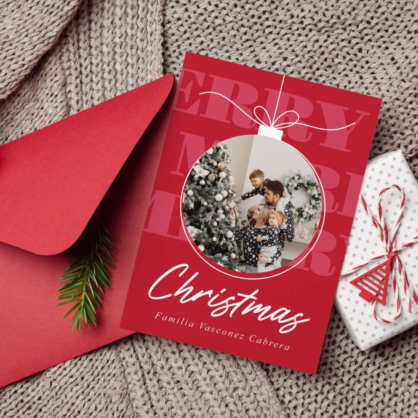mockup de tarjeta con foto navideña junto a un sobre rojo un regalo y una manta tejida