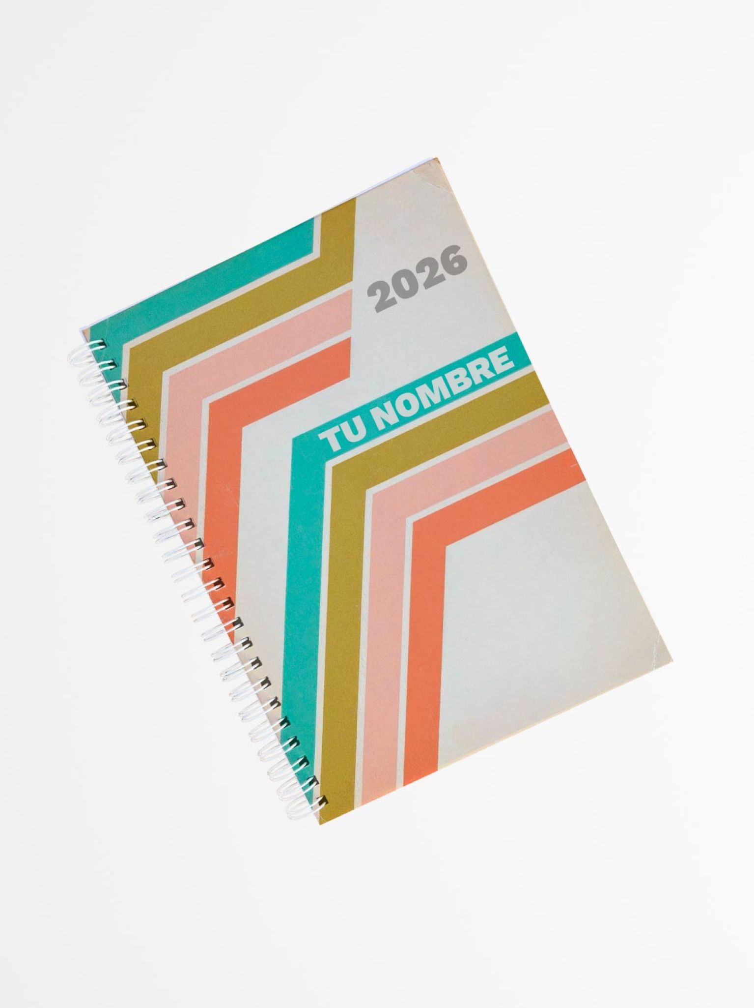 vista superior de una agenda con portada vintage, fondo beige y franjas diagonales en tonos verde, coral y mostaza, encuadernada con espiral lateral