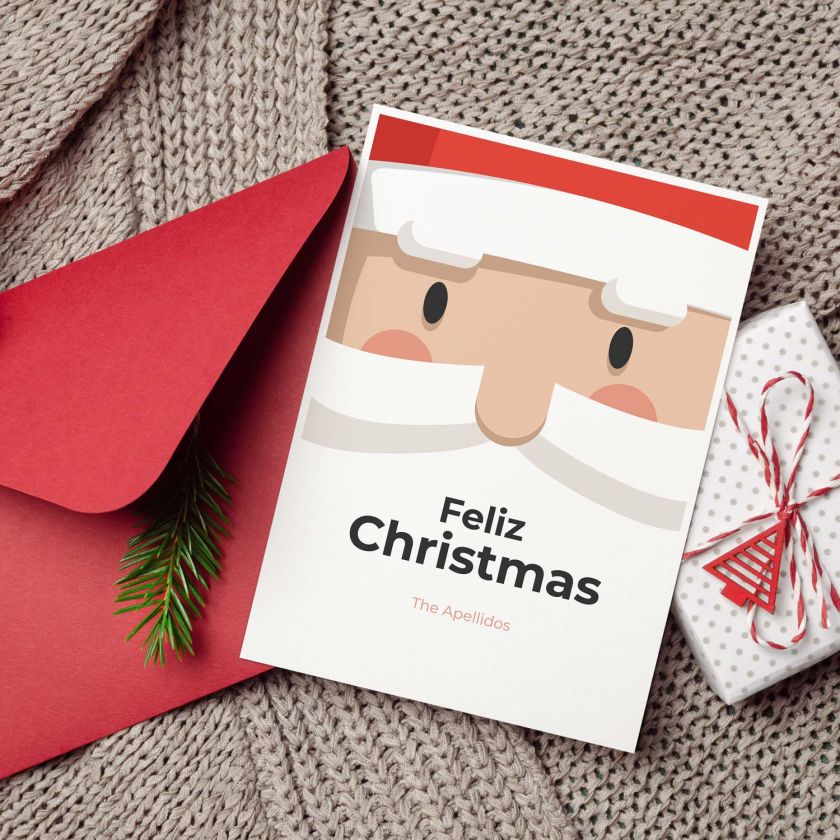 Tarjeta de Navidad con Papá Noel junto a sobre rojo, decoración y regalo navideño
